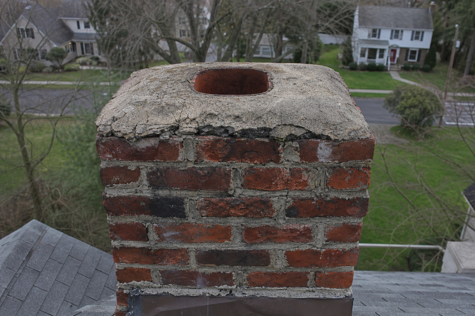 Weathered brick chimney with no cap and an exposed flue opening